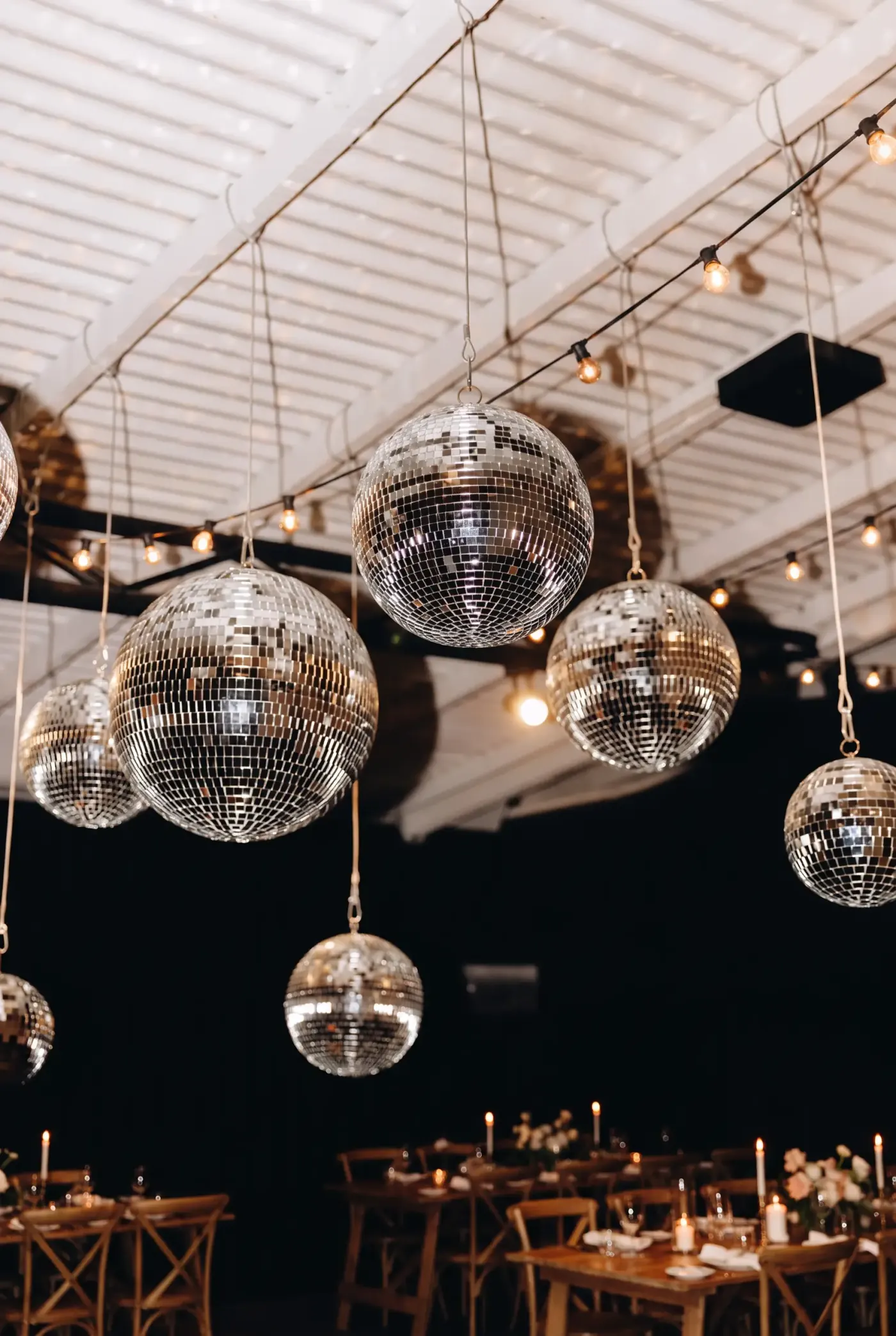 Looking up to the white timber warehouse ceiling, mirrored disco balls catching warm light