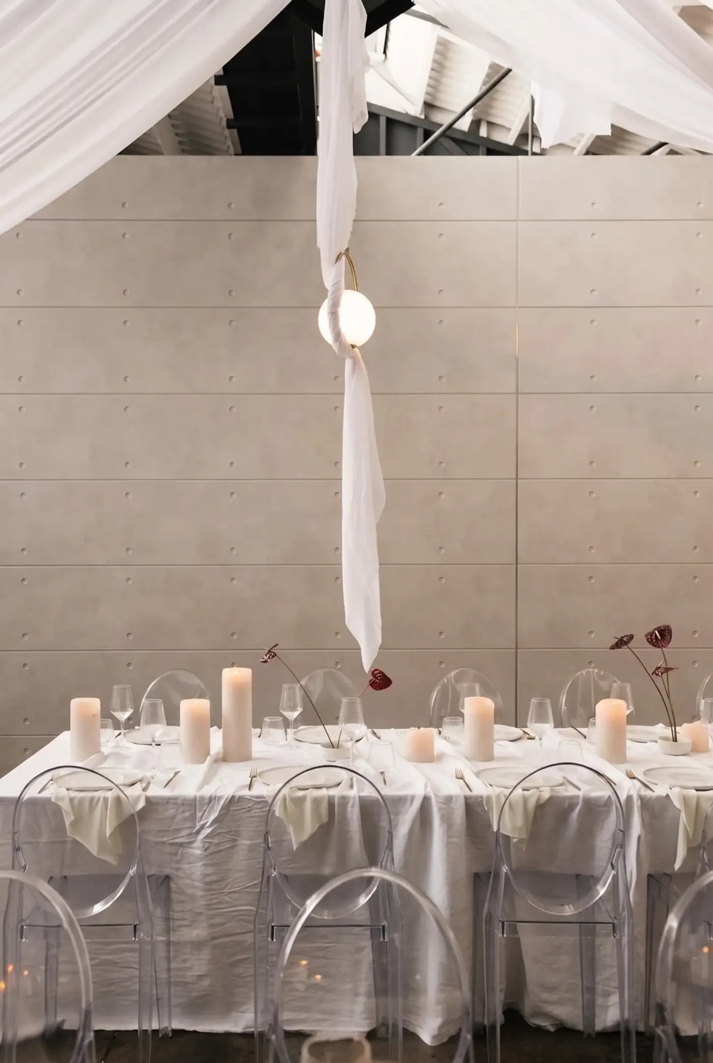 Standing at the dressed table, pillar candles against the concrete wall