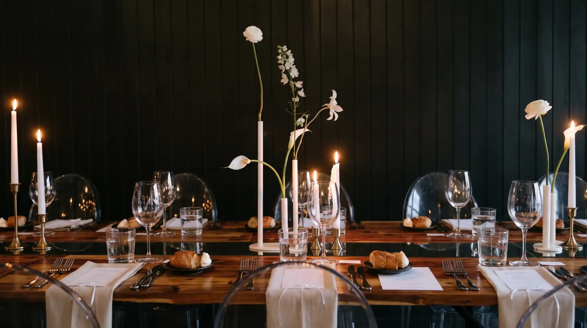 A seated guest's view along the timber table, tapered candles in deep candlelight