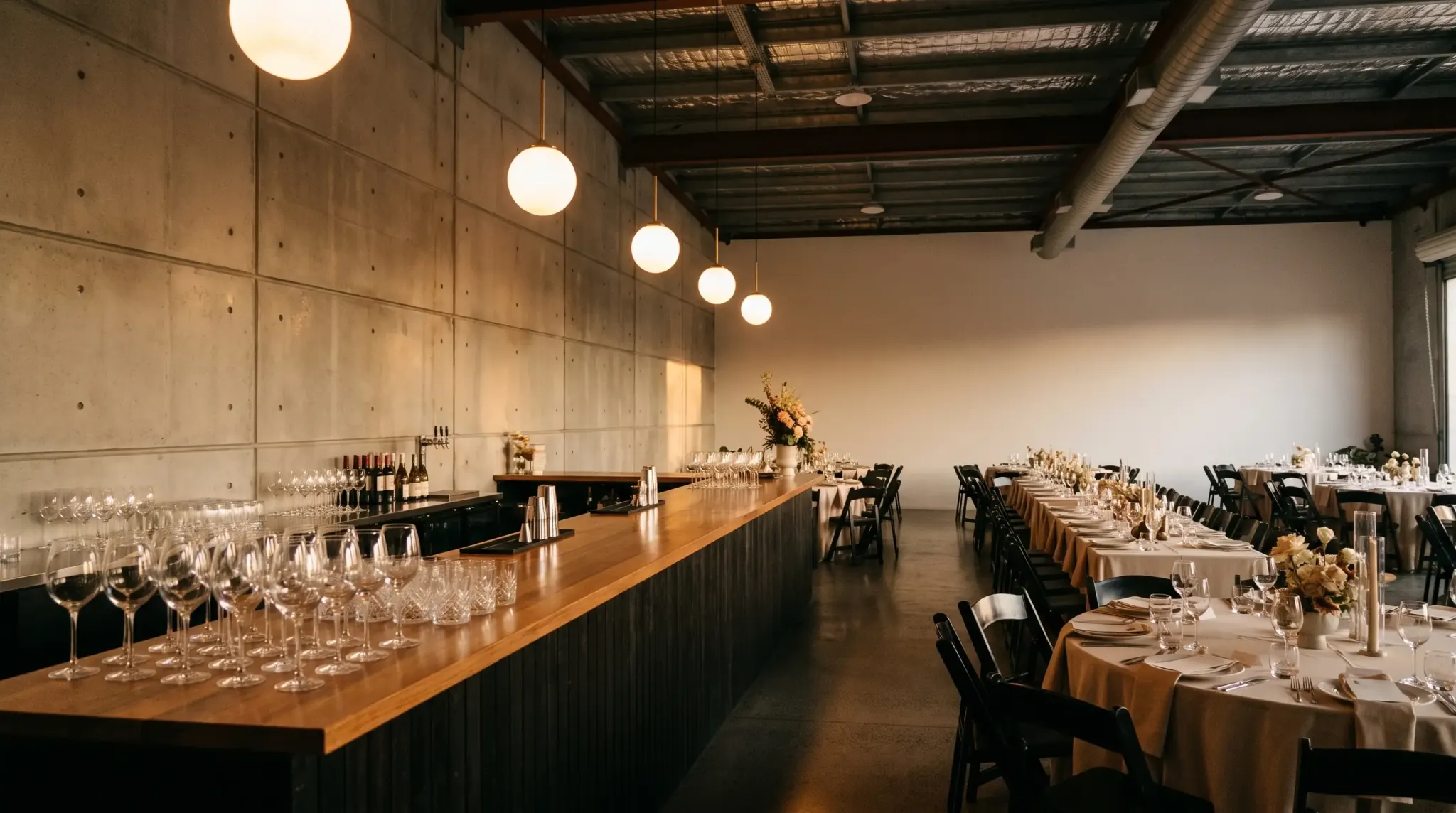 The bar along the side of the room, glassware under warm pendant globes